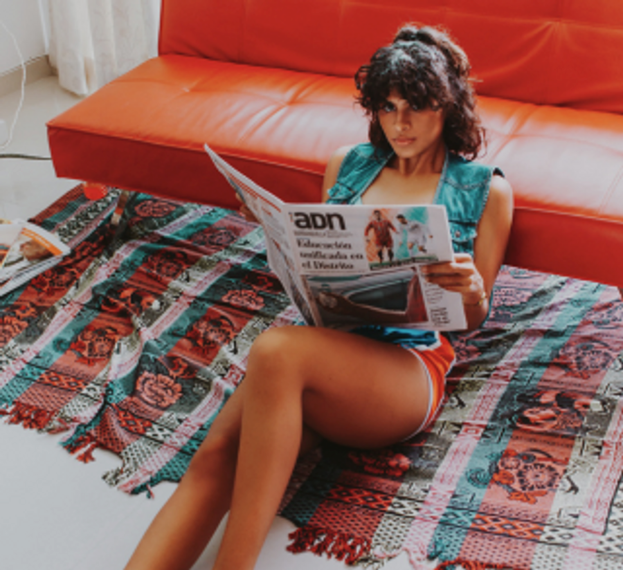 Dziewczyna siedzi na ziemii z gazetą